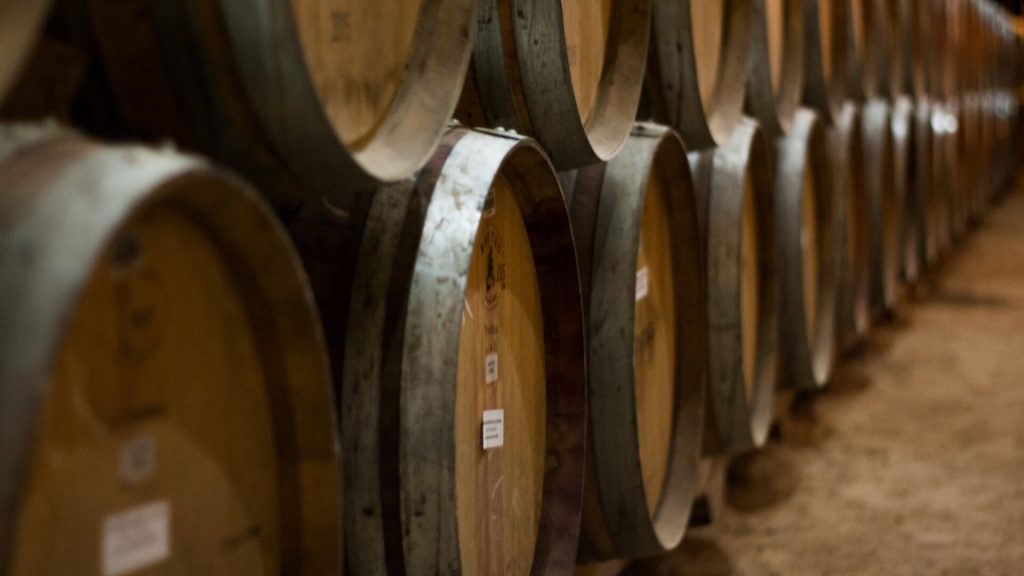 A storage room packed with rows of oak barrels, aging fine wines or spirits.